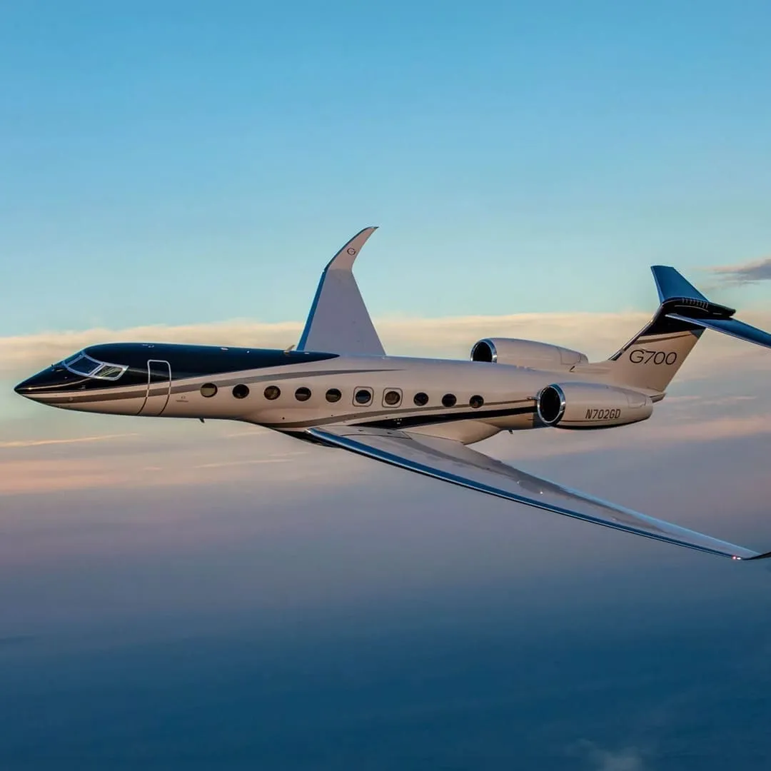 A private jet in flight above the clouds at sunset